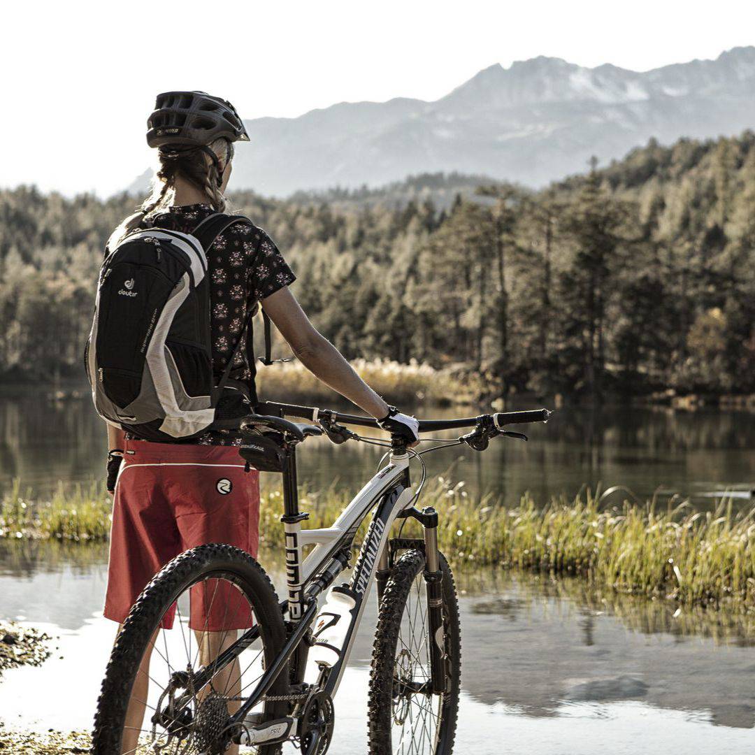 Mädchen steht mit ihrem Mountainbike vor einem See in Tirol.