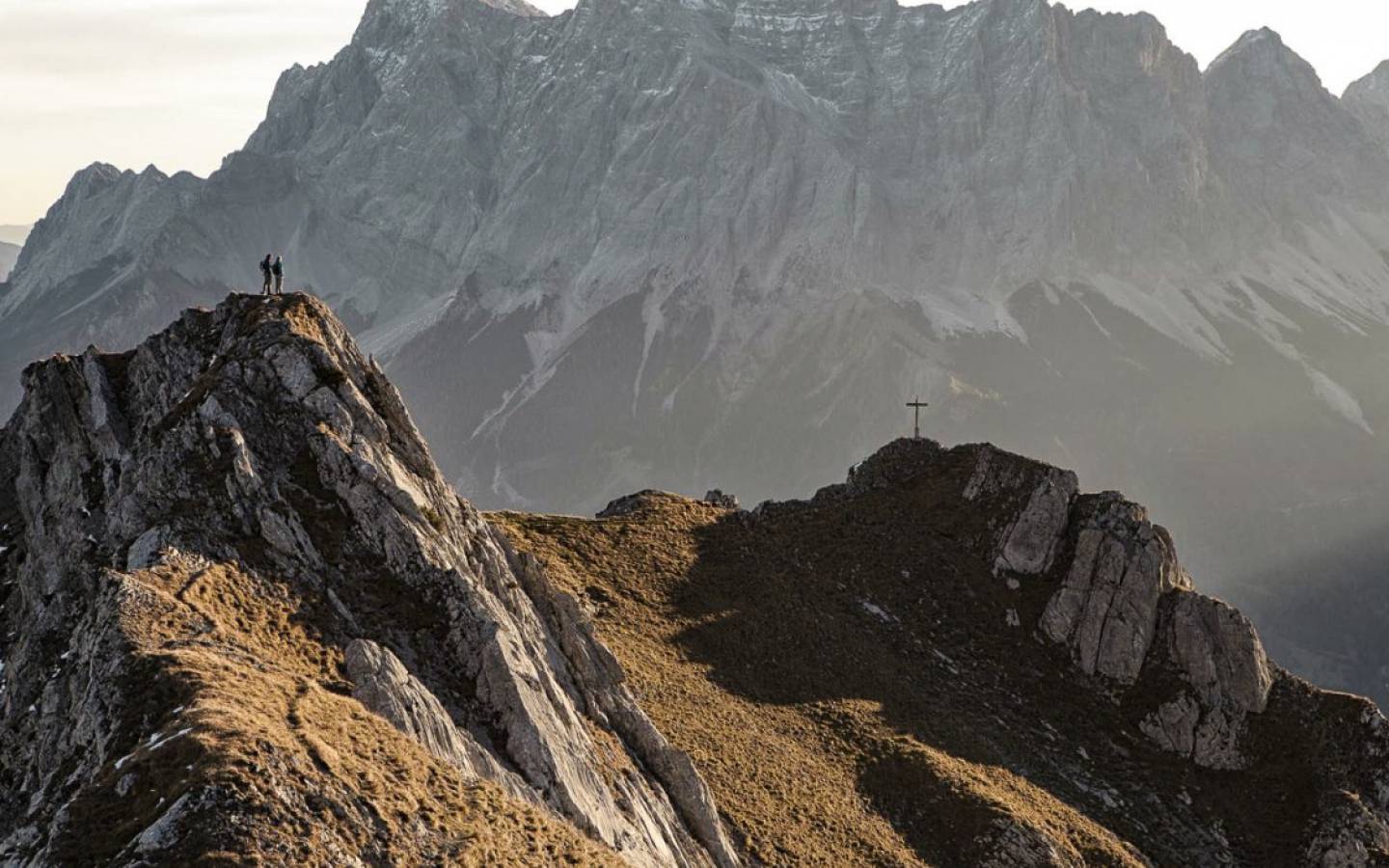Wanderer in den Alpen beim Gipfelkreuz