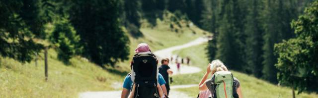 Familie mit Kinderwagen und Rucksack auf einer familienfreundlichen Wanderung.