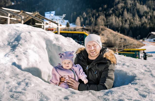 Ein Vater steht mit seinem Baby im Schnee.