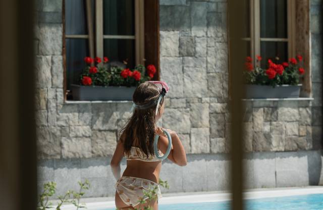 Mädchen steht vor dem Außenpool des Hotels Tirolerhof in Tirol.