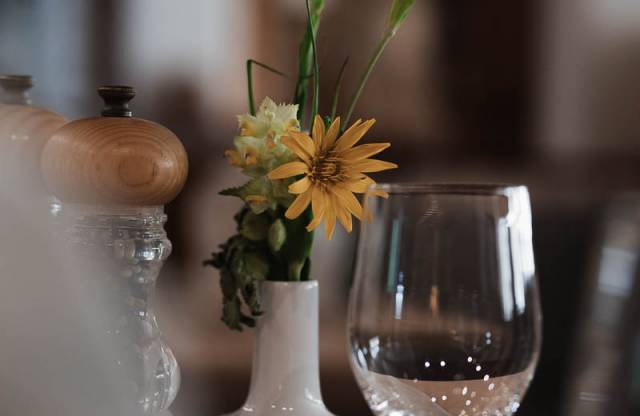 Liebevoll gedeckter Tisch mit Blumen und Weinglas im Restaurant des Familienhotels Tirolerhofs.