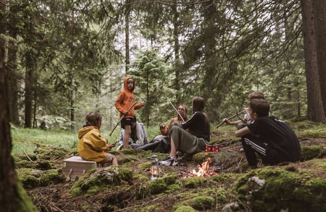 Kinder im Wald beim Feuer machen.