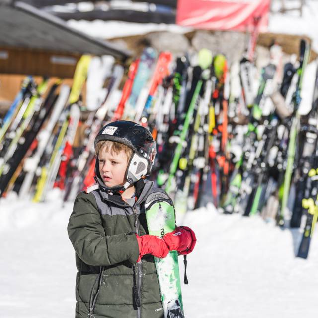 Kind steht mit seinen Skiern im Skigebiet in den Tiroler Bergen.