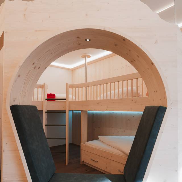 Gemütlicher Sitzbereich mit Holzelementen und Stockbett im Familienzimmer.