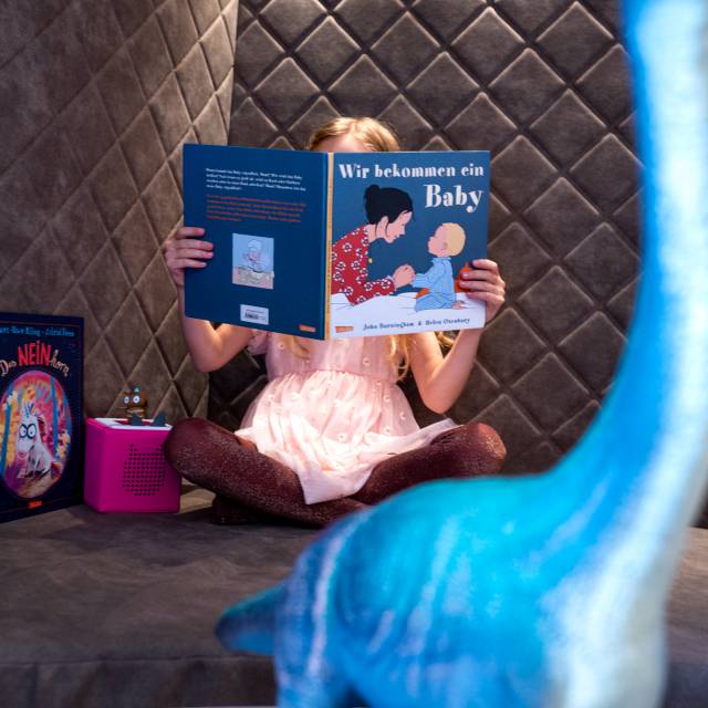 Girl reading a book on a cozy sofa at Tirolerhof.
