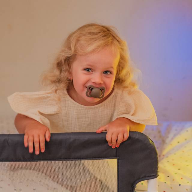 Toddler laughing happily on the bed at the family hotel.
