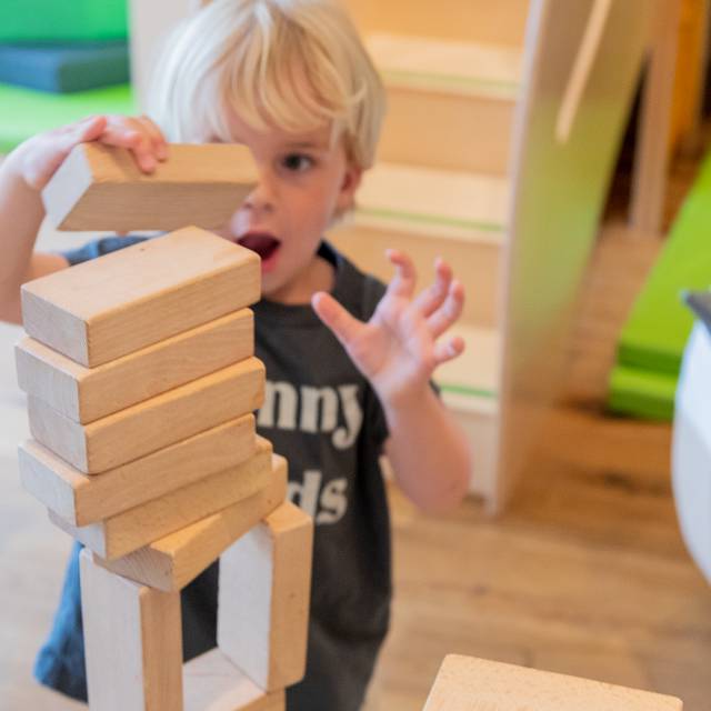 Toddler playing with wooden building blocks in the kids' club at Tirolerhof.