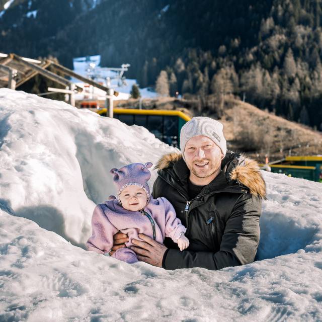 Ein Vater steht mit seinem Baby im Schnee.