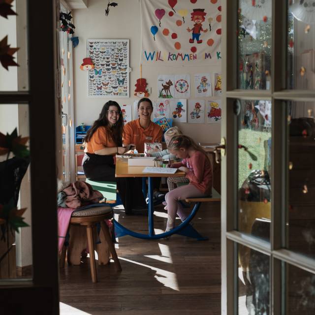 Lächelnde Kinderbetreuerinnen mit Kindern im bunt gestalteten Happy Club im Tirolerhof.