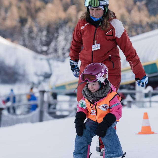Kind lernt Ski fahren mit Skilehrerin.
