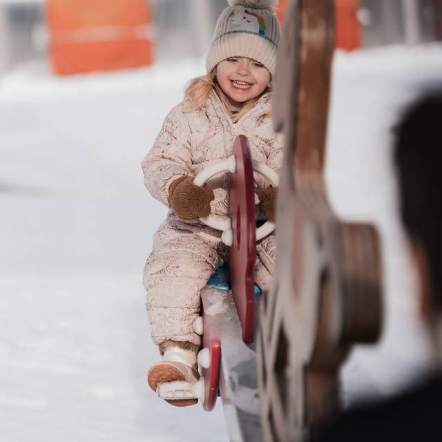 Mädchen spielt auf einem Spielplatz im Winter bei Schnee in Tirol.