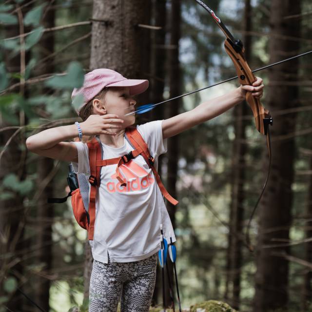 Little child doing archery in the forest.