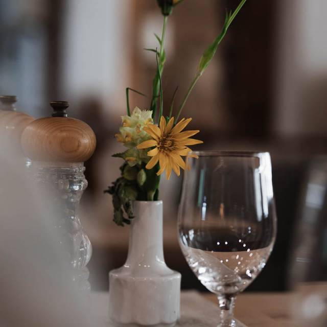 Liebevoll gedeckter Tisch mit Blumen und Weinglas im Restaurant des Familienhotels Tirolerhofs.