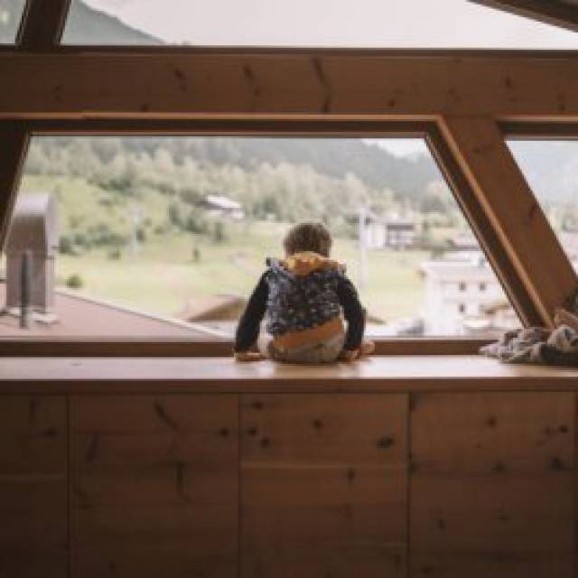 Kinder sitzen auf einem Holzbalken mit Blick nach außen.