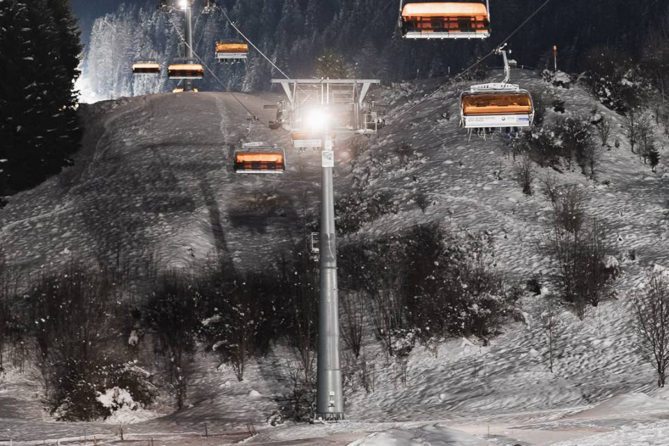 Gruppe beim Nachtrodeln unter einem Skilift in den Tiroler Bergen.