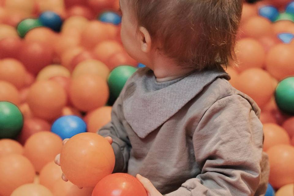 Toddler sitting in the ball pit at the hotel.