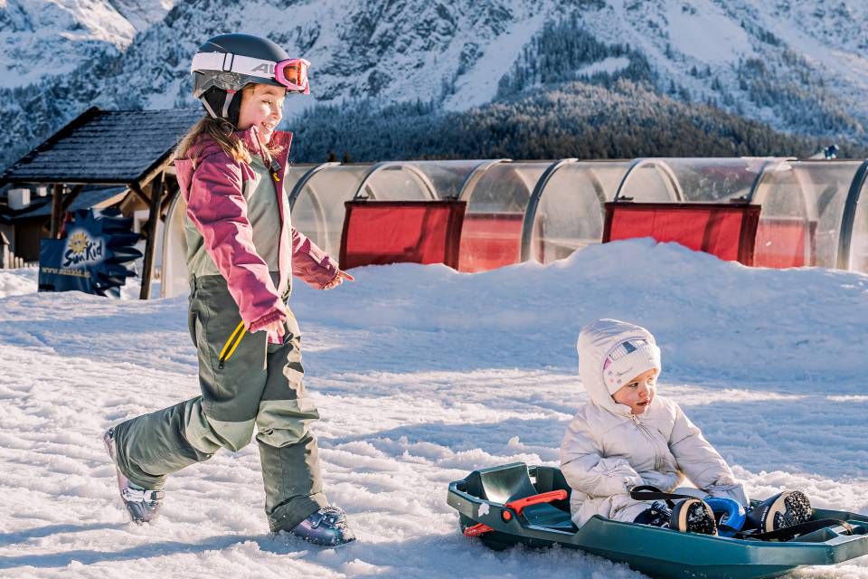 Kind fährt mit Baby Schlitten im Zugspitzareal.