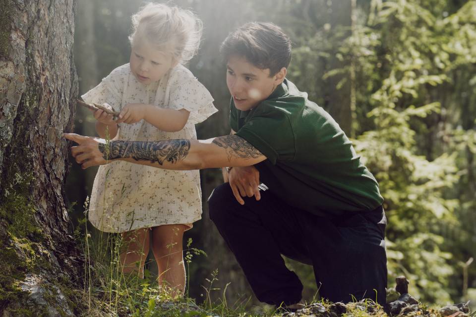 Kinderbetreuer und Kind entdecken gemeinsam den Wald in Ehrwald.