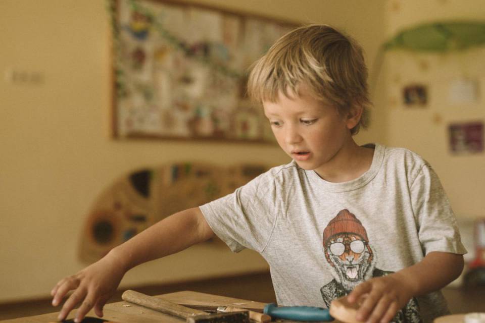 Kind geht einer handwerklichen Tätigkeit in der Kinderbetreuung im Tirolerhof nach.