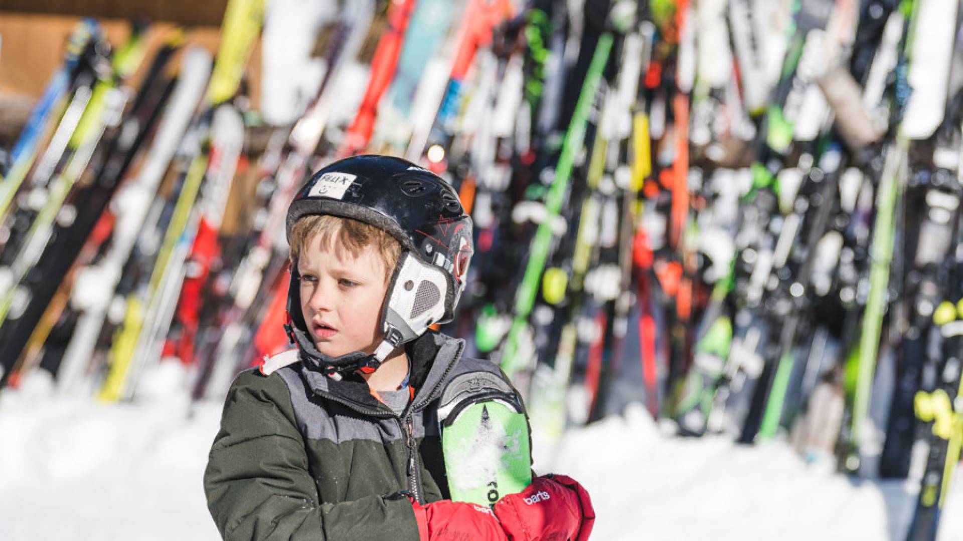 Kind steht mit seinen Skiern im Skigebiet in den Tiroler Bergen.