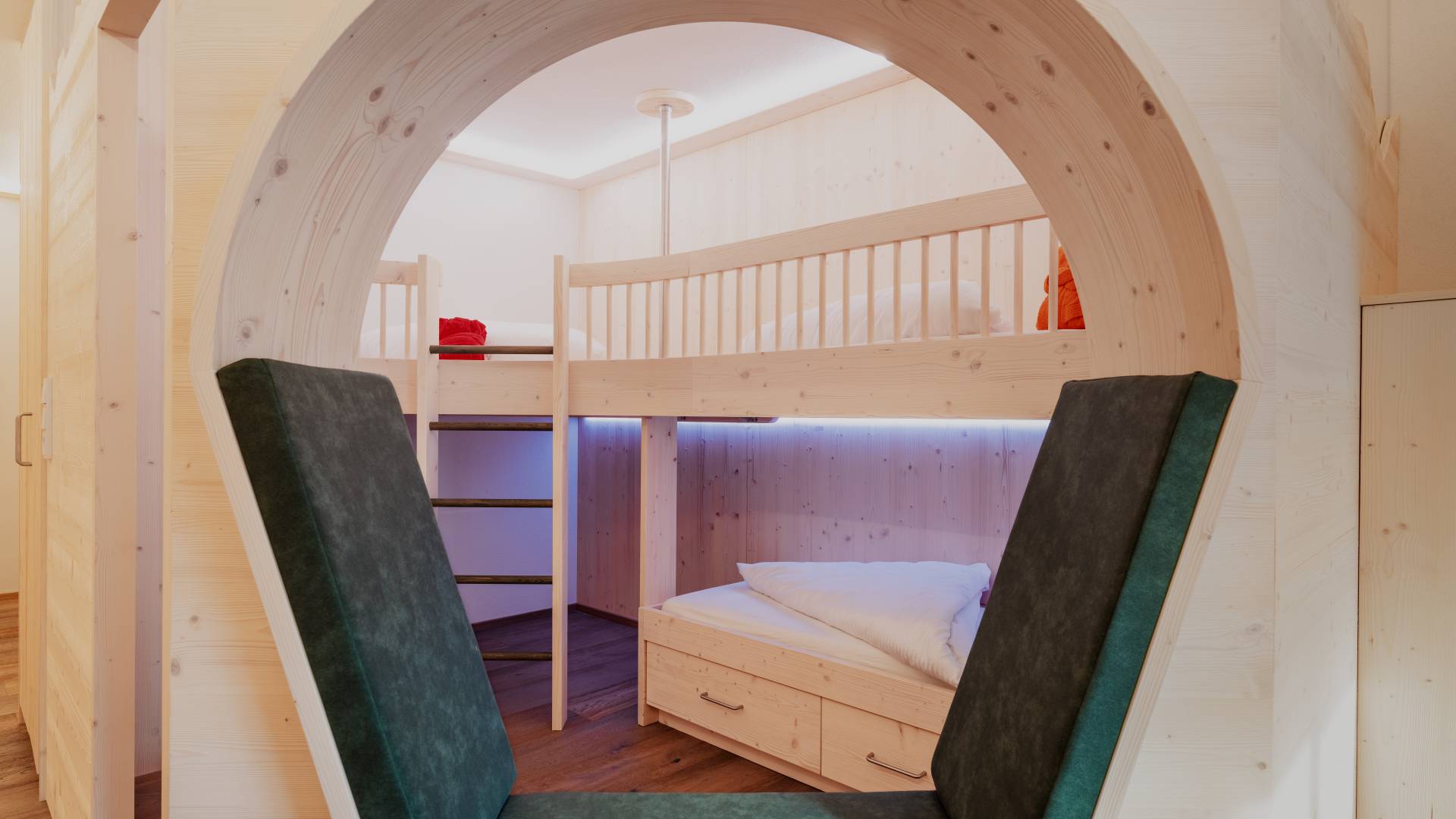 Helles Familienzimmer mit Stockbett und Sitzgelegenheit.