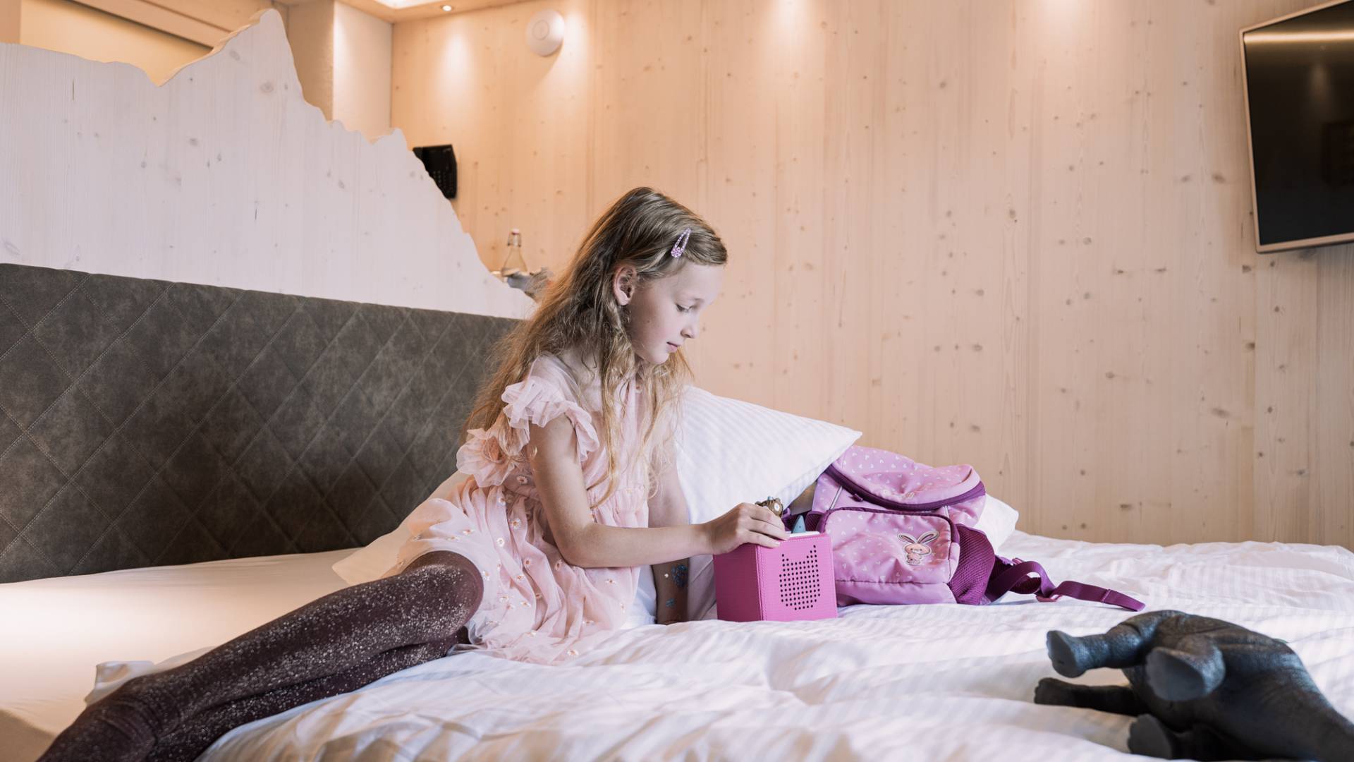Mädchen sitzt auf einem Bett in einem modernen Hotelzimmer.