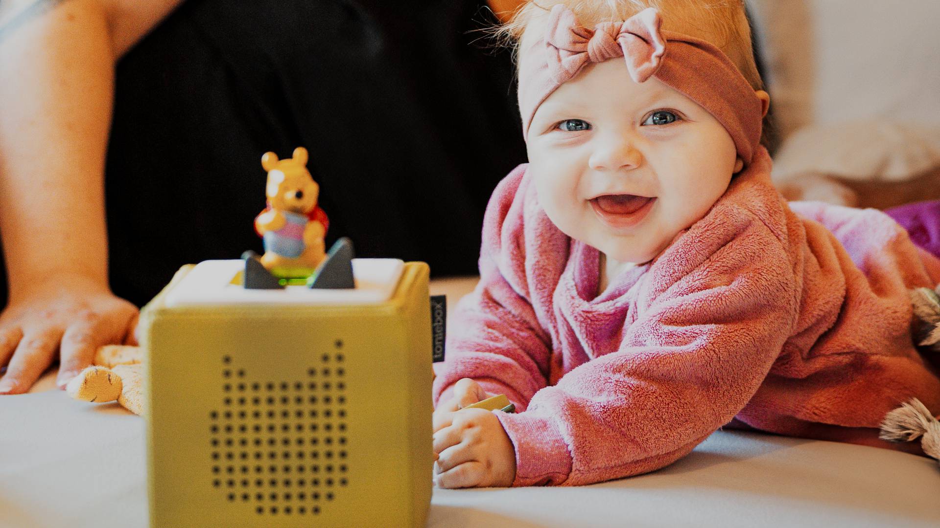 Baby lying relaxed on the bed with mom, listening to the sounds of the music box.