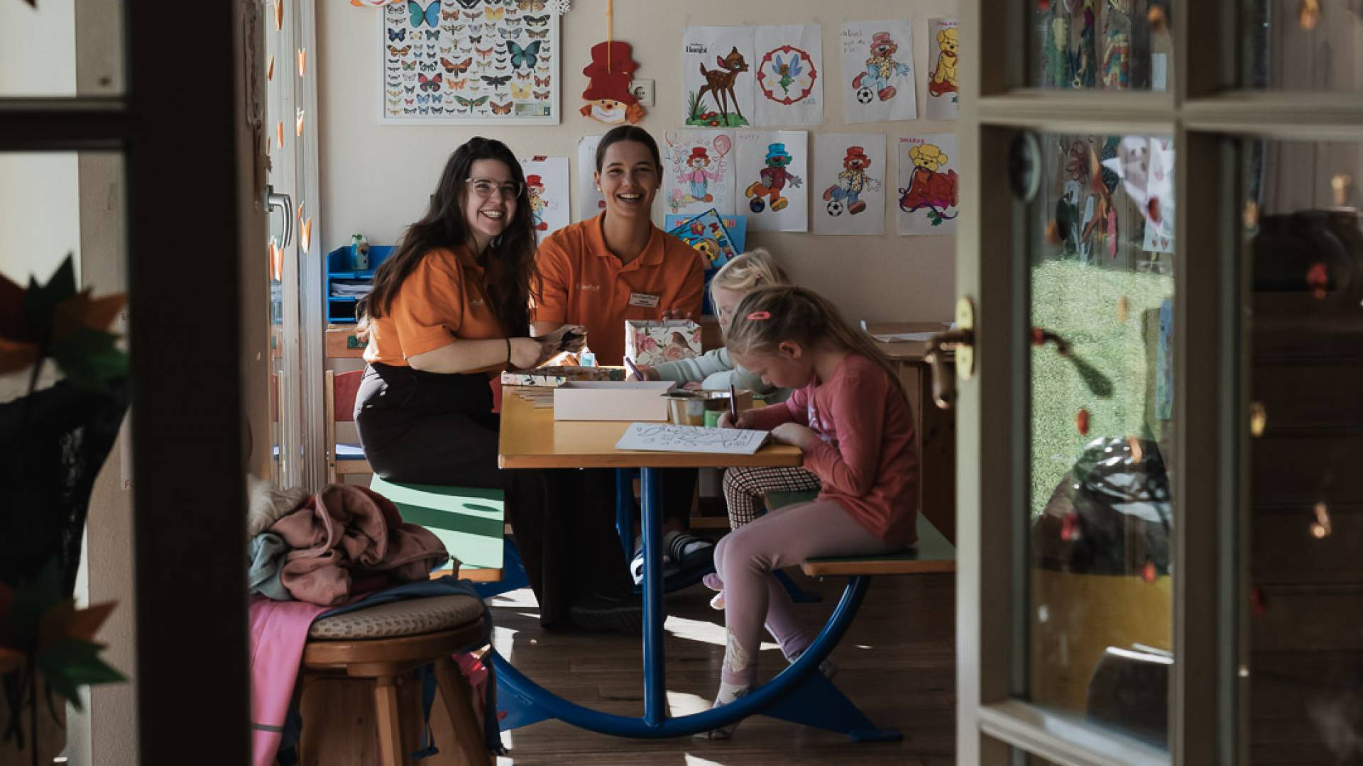 Lächelnde Kinderbetreuerinnen mit Kindern im bunt gestalteten Happy Club im Tirolerhof.