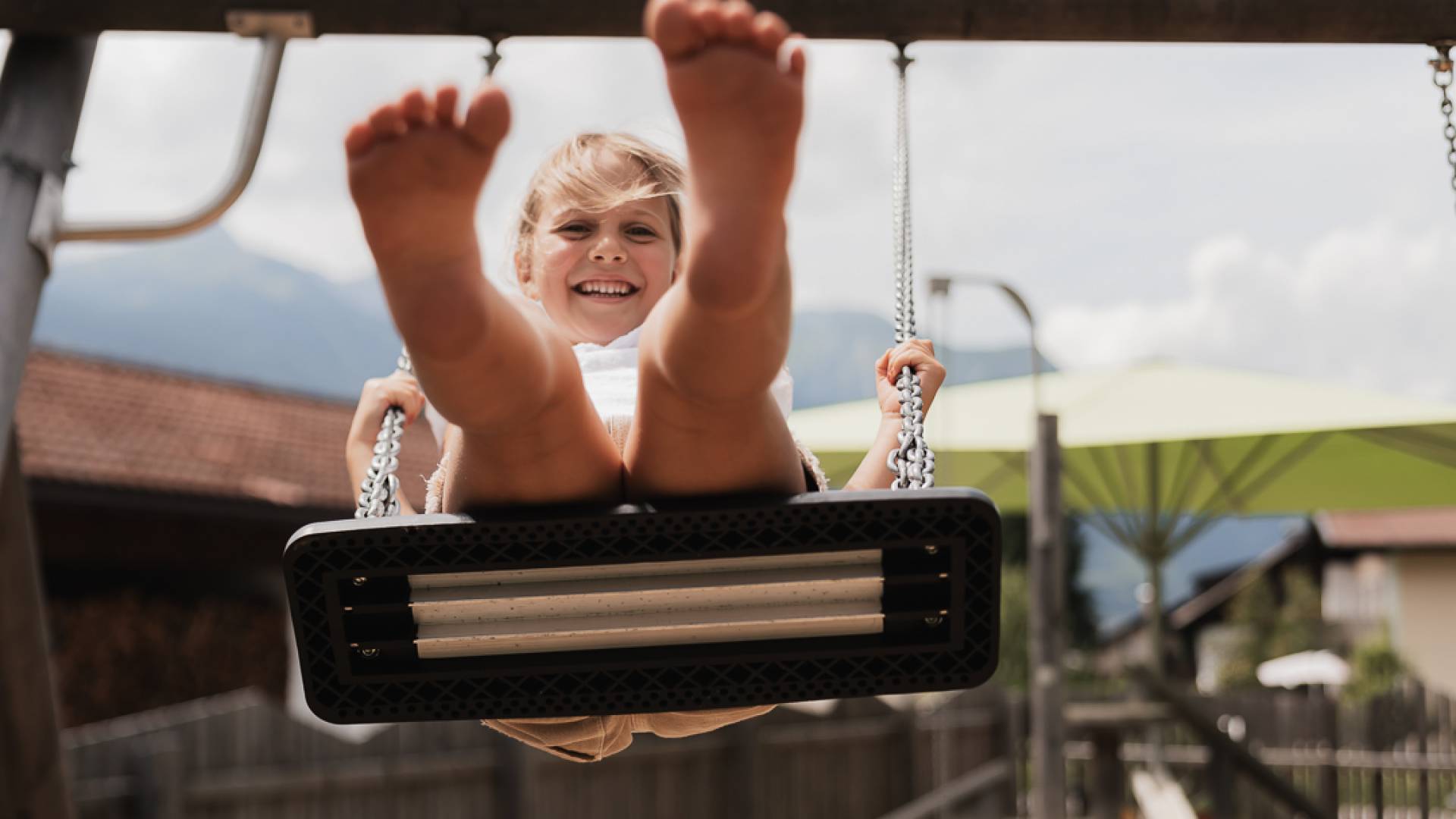 Kind schaukelt auf dem Spielplatz im Familienhotel Tirolerhof.