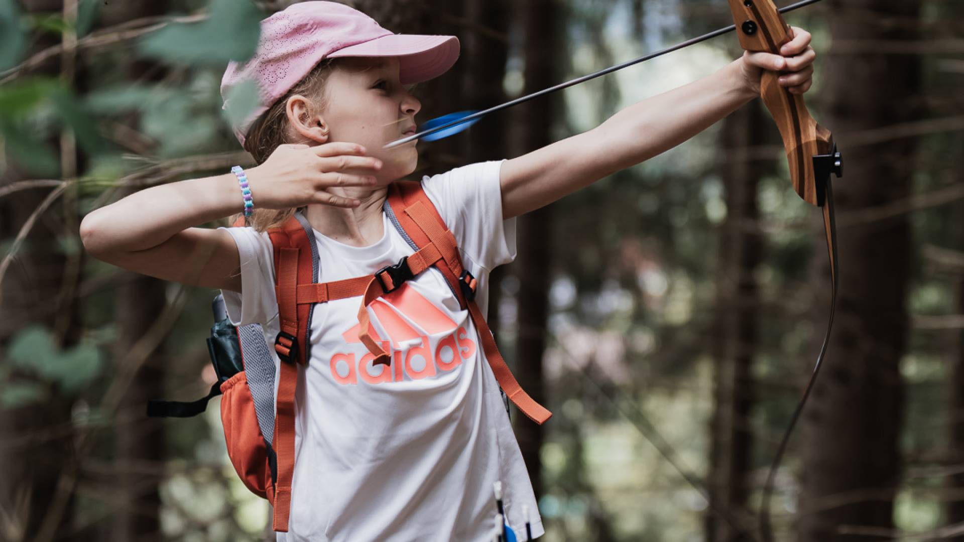 Little child doing archery in the forest.