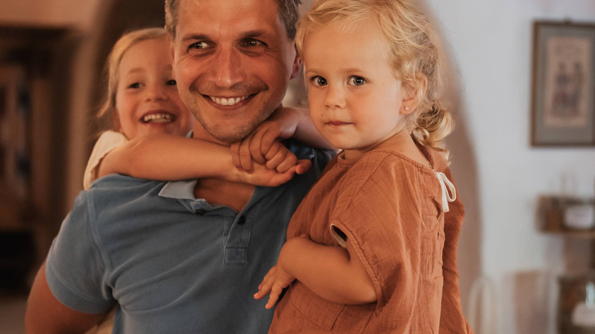 Papa hält zwei Kindern in den Armen.