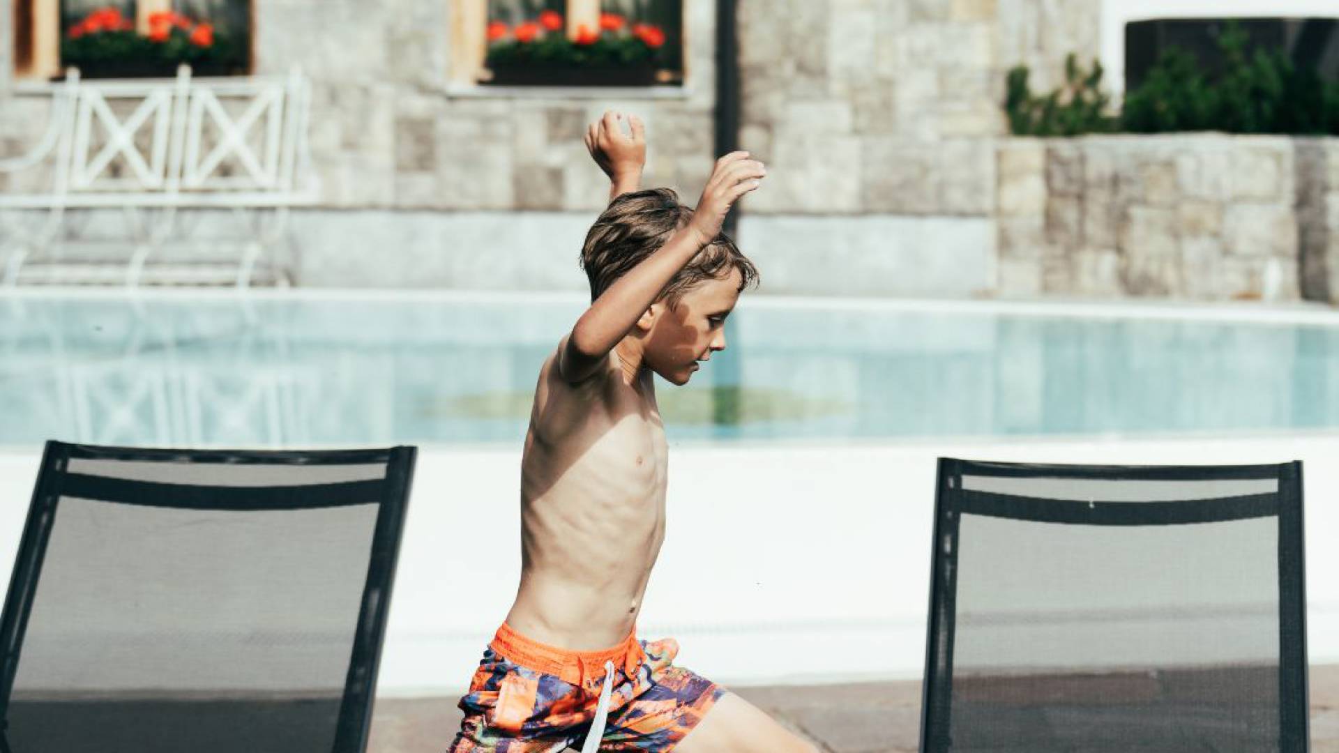 Ein Junge in Badehose rennt um den Außenpool des Tirolerhofs.