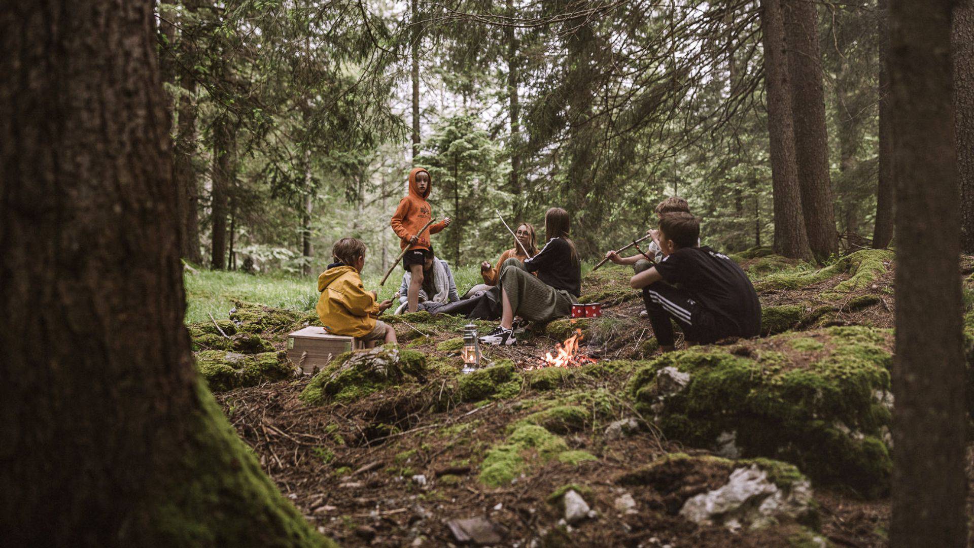 Kinder sitzen am Lagerfeuer im Wald in Ehrwald.